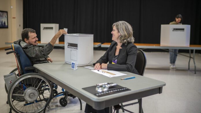 An elector in a wheelchair casting a ballot at a polling station